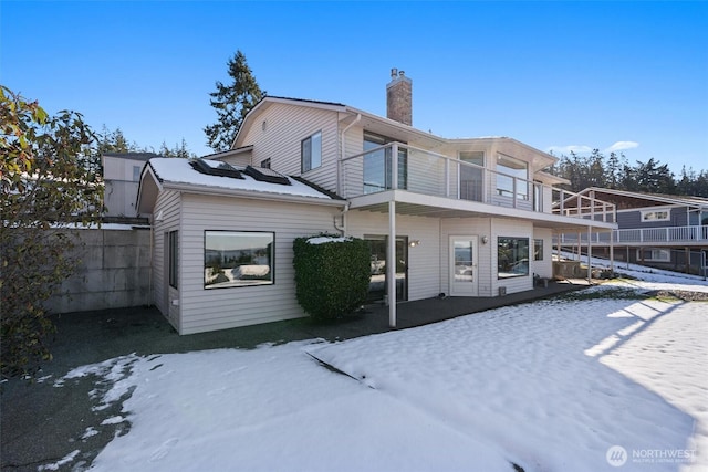 snow covered back of property with a balcony