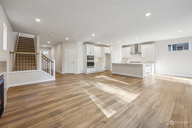 unfurnished living room with sink and light hardwood / wood-style floors