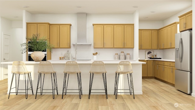 kitchen with tasteful backsplash, an island with sink, a breakfast bar, and stainless steel fridge