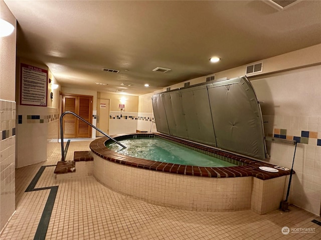 interior space with a hot tub, tile walls, and light tile patterned floors