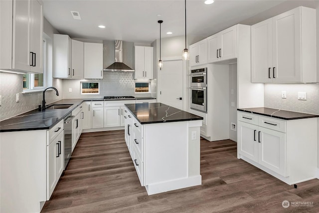 kitchen with white cabinetry, wall chimney exhaust hood, a center island, and sink