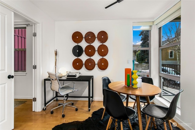 dining area with a wall of windows, baseboards, and wood finished floors