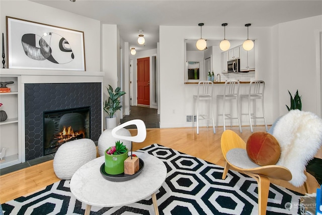 living area featuring a tiled fireplace and wood finished floors