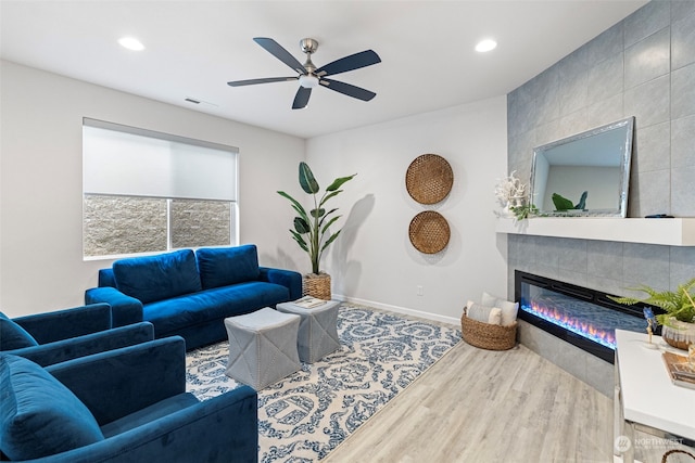 living room featuring ceiling fan, hardwood / wood-style floors, and a tile fireplace