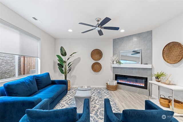 living room featuring a tiled fireplace and ceiling fan