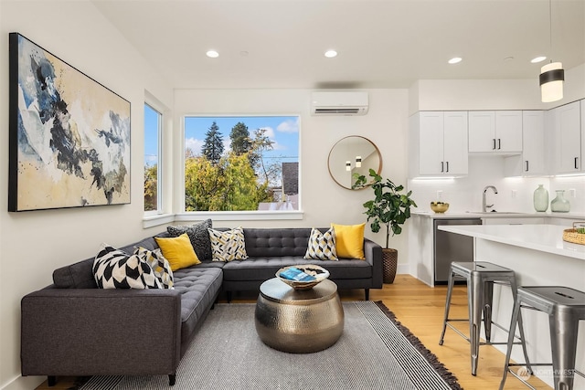 living room featuring sink, a wall mounted air conditioner, and light wood-type flooring