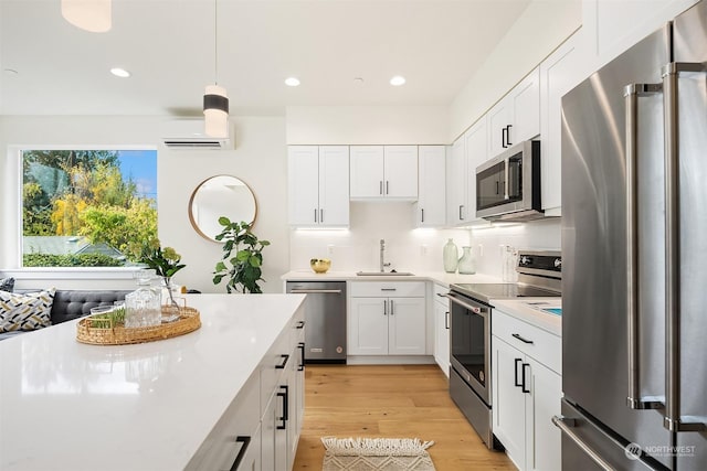 kitchen with sink, appliances with stainless steel finishes, white cabinetry, a wall mounted air conditioner, and decorative light fixtures