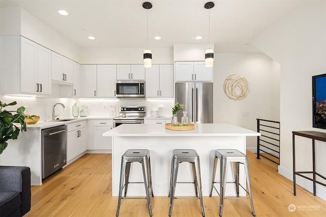 kitchen featuring stainless steel appliances, white cabinetry, a kitchen island, and sink