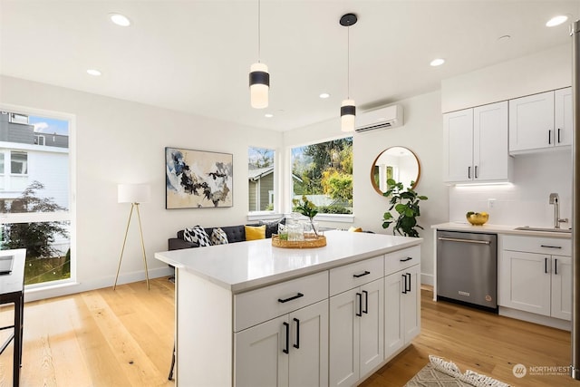 kitchen with a wall mounted air conditioner, decorative light fixtures, white cabinetry, sink, and stainless steel dishwasher