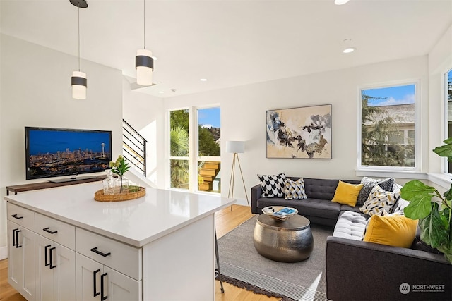 kitchen featuring white cabinetry, a kitchen island, light hardwood / wood-style flooring, and decorative light fixtures