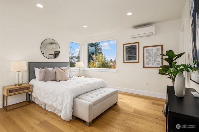 bedroom with light hardwood / wood-style floors and an AC wall unit