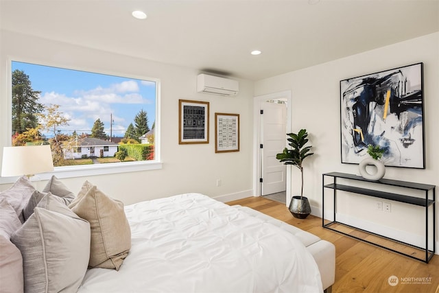 bedroom with a wall mounted air conditioner and light wood-type flooring