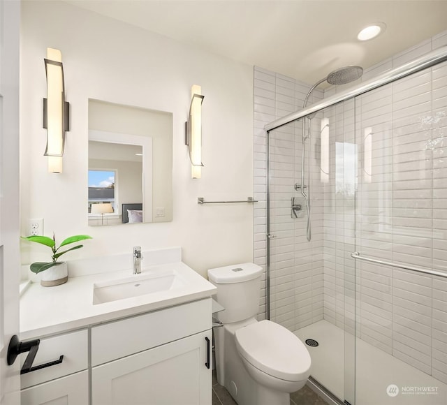 bathroom featuring vanity, toilet, and a shower with door