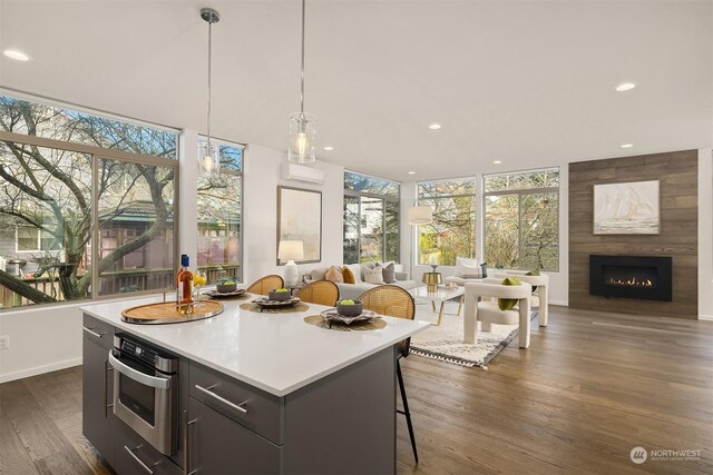 kitchen with hanging light fixtures, a center island, a fireplace, dark hardwood / wood-style flooring, and oven