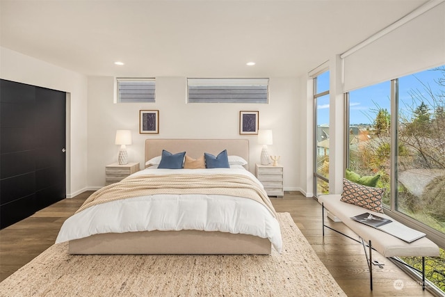 bedroom with dark hardwood / wood-style flooring and a wall of windows