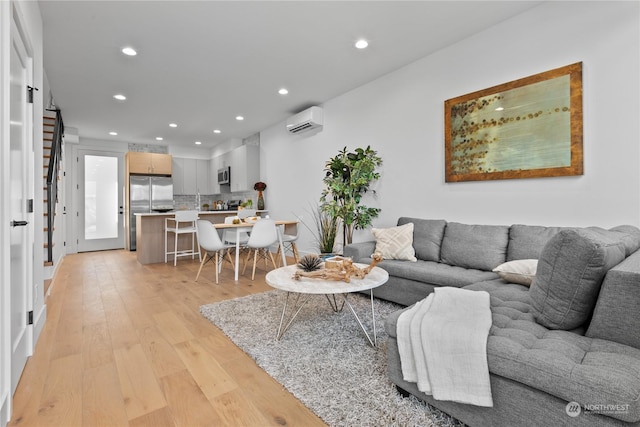 living room with a wall unit AC and light hardwood / wood-style flooring