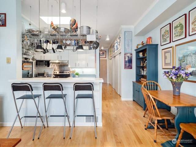 kitchen with pendant lighting, a kitchen breakfast bar, stainless steel appliances, white cabinets, and kitchen peninsula