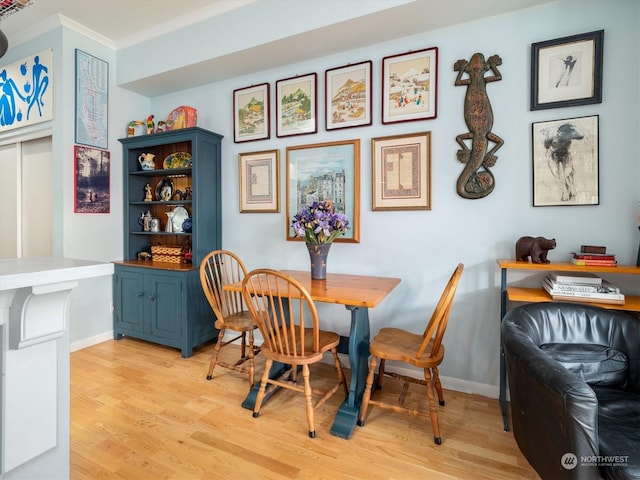 dining area with crown molding and light hardwood / wood-style floors