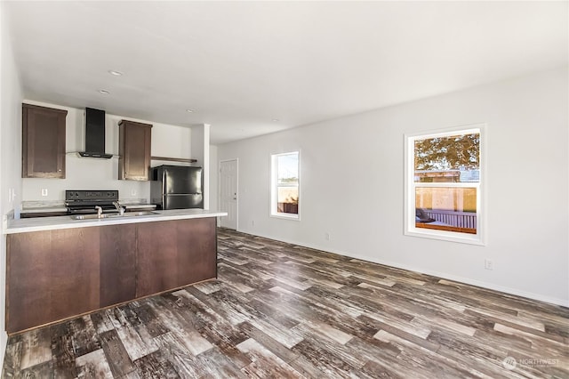 kitchen with dark hardwood / wood-style floors, stainless steel fridge, range, dark brown cabinetry, and wall chimney exhaust hood