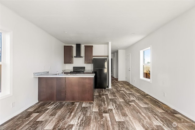 kitchen with dark wood-type flooring, wall chimney range hood, kitchen peninsula, and black appliances