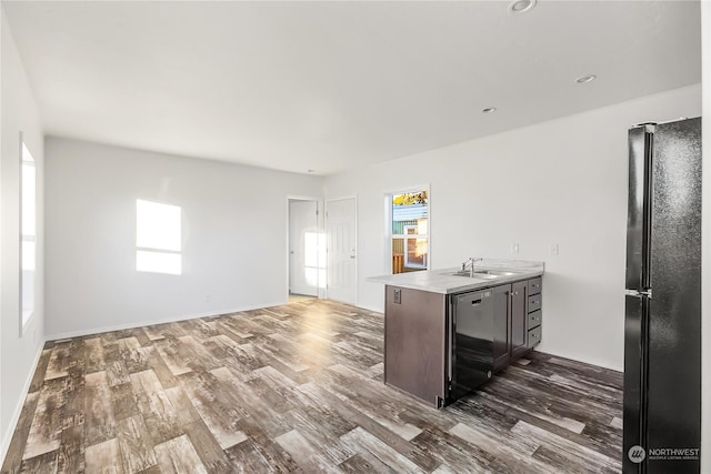 kitchen with dark brown cabinetry, sink, dark hardwood / wood-style flooring, kitchen peninsula, and black appliances