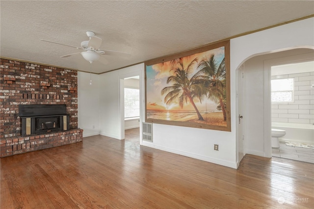 unfurnished living room with ceiling fan, wood-type flooring, ornamental molding, and a textured ceiling