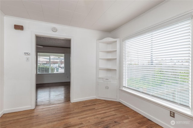 unfurnished room with hardwood / wood-style floors, crown molding, and a healthy amount of sunlight