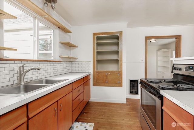 kitchen featuring sink, electric range, heating unit, decorative backsplash, and light wood-type flooring