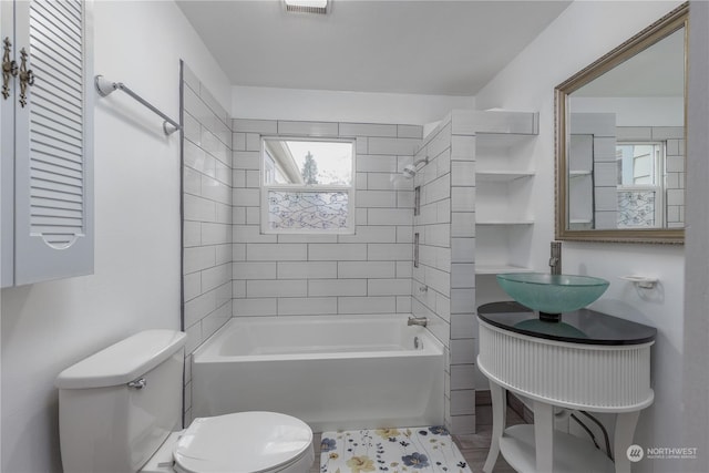 full bathroom featuring toilet, tiled shower / bath combo, and sink