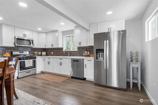 kitchen with sink, white cabinetry, dark hardwood / wood-style flooring, stainless steel appliances, and decorative backsplash