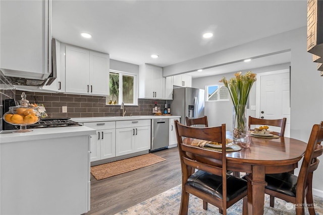 kitchen featuring appliances with stainless steel finishes, white cabinetry, sink, dark hardwood / wood-style flooring, and decorative backsplash