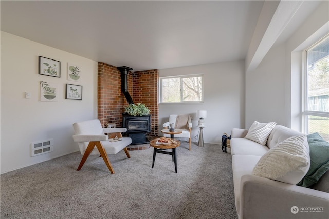 living room featuring plenty of natural light, carpet flooring, and a wood stove