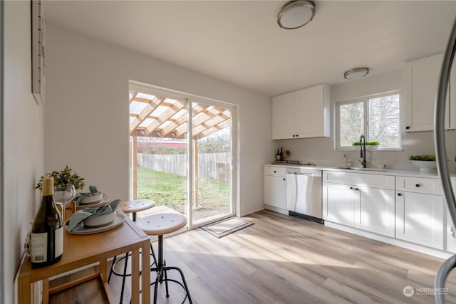 kitchen featuring white cabinetry, sink, light hardwood / wood-style flooring, and stainless steel dishwasher