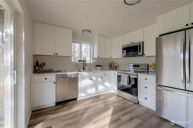 kitchen with white cabinetry, sink, light hardwood / wood-style floors, and appliances with stainless steel finishes