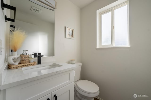 bathroom featuring vanity, a wealth of natural light, and toilet