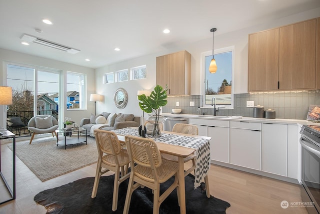 kitchen with pendant lighting, tasteful backsplash, white cabinetry, sink, and stainless steel appliances