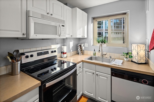 kitchen with appliances with stainless steel finishes, sink, and white cabinets