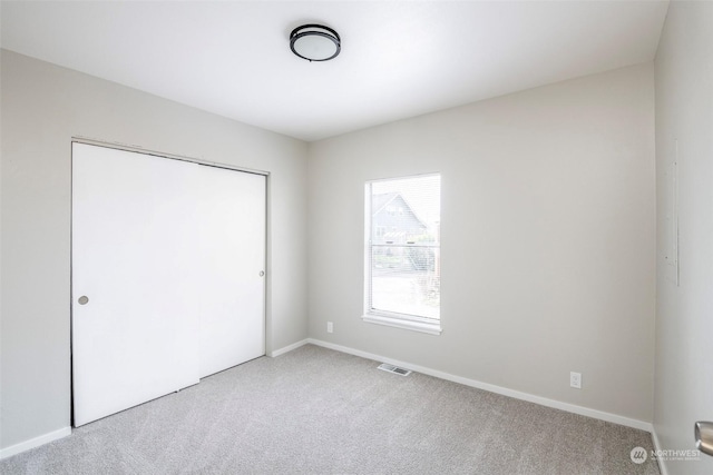 unfurnished bedroom featuring light colored carpet and a closet