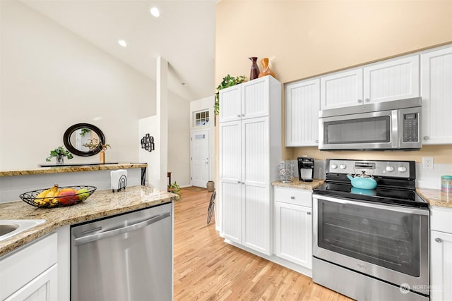 kitchen with appliances with stainless steel finishes, light stone countertops, light hardwood / wood-style flooring, and white cabinets