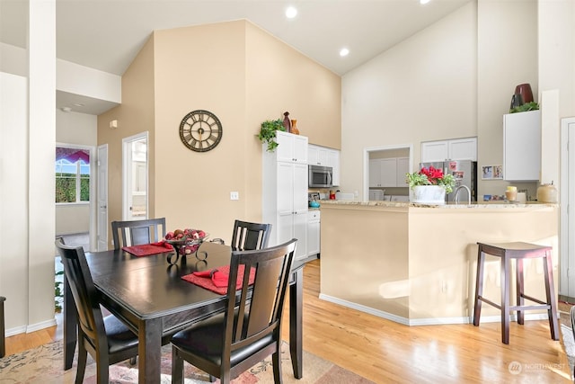 dining space with light hardwood / wood-style flooring and high vaulted ceiling