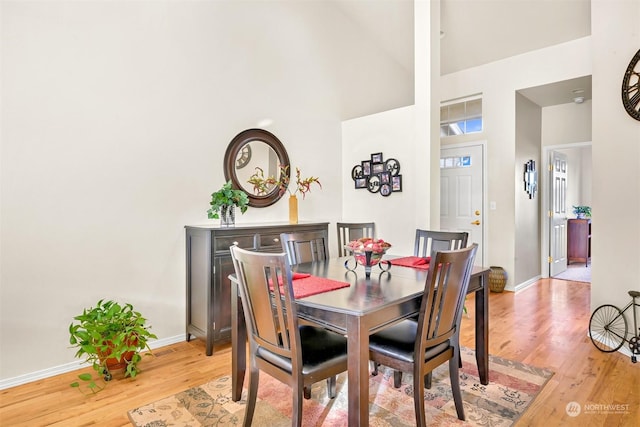 dining room featuring a towering ceiling and light hardwood / wood-style flooring