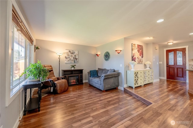 interior space featuring wood finished floors, recessed lighting, a glass covered fireplace, and baseboards