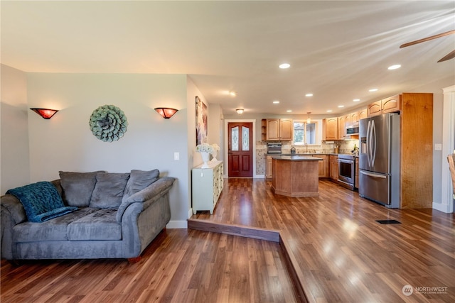 living area featuring baseboards, dark wood finished floors, a ceiling fan, and recessed lighting