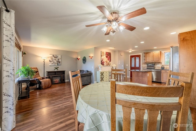 dining space with recessed lighting, a glass covered fireplace, ceiling fan, wood finished floors, and baseboards