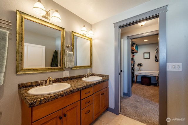 bathroom with double vanity, tile patterned flooring, a sink, and baseboards