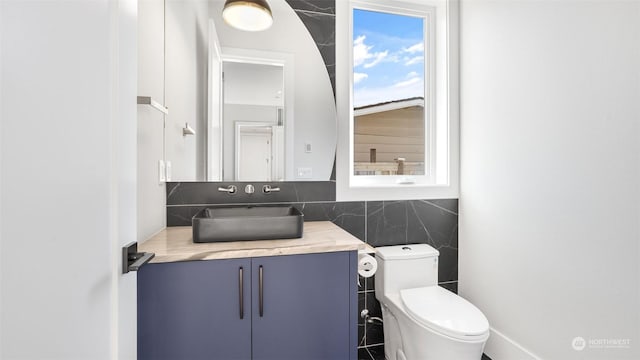 bathroom with vanity, tile walls, and toilet