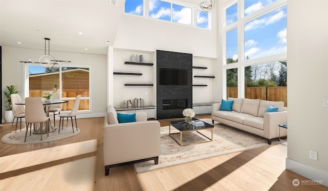 living room with wood-type flooring, a fireplace, an inviting chandelier, and baseboard heating