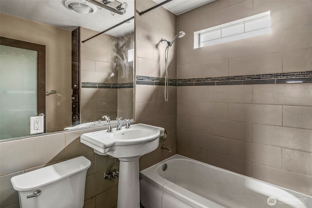 bathroom featuring toilet, tile walls, and shower / bathing tub combination