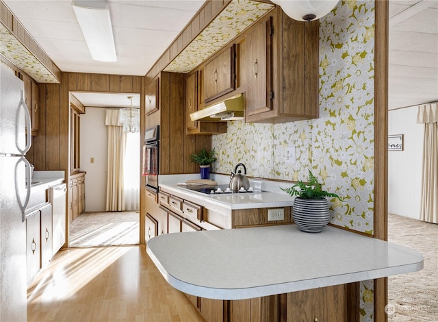 kitchen with electric cooktop, hanging light fixtures, dishwasher, kitchen peninsula, and oven