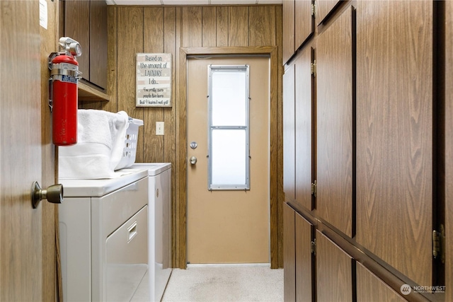 laundry room featuring light colored carpet, cabinets, washing machine and dryer, and wood walls